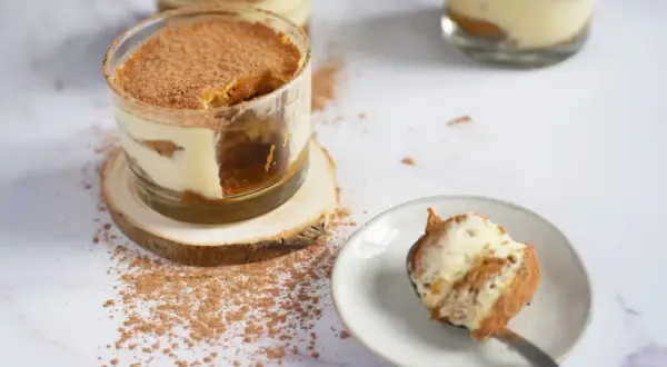 Tiramisu en verrine saupoudré de cacao, avec une cuillère garnie.