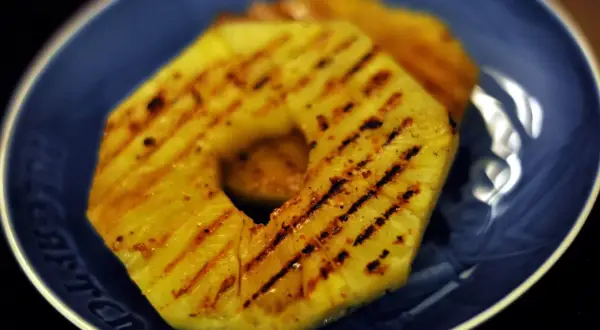 Tranches d'ananas grillées sur une assiette bleue.