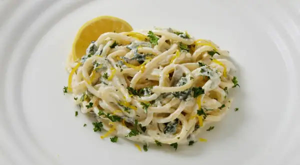 Pâtes crémeuses au citron et persil, garnies d'une tranche de citron.