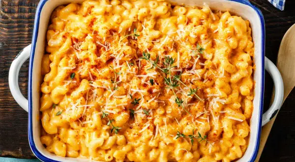 Gratin de pâtes crémeux et doré, garni de fromage râpé et de thym frais.