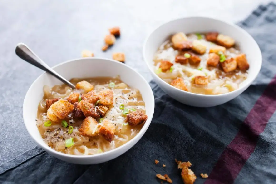 Deux bols de soupe à l'oignon gratinée avec croûtons et ciboule.