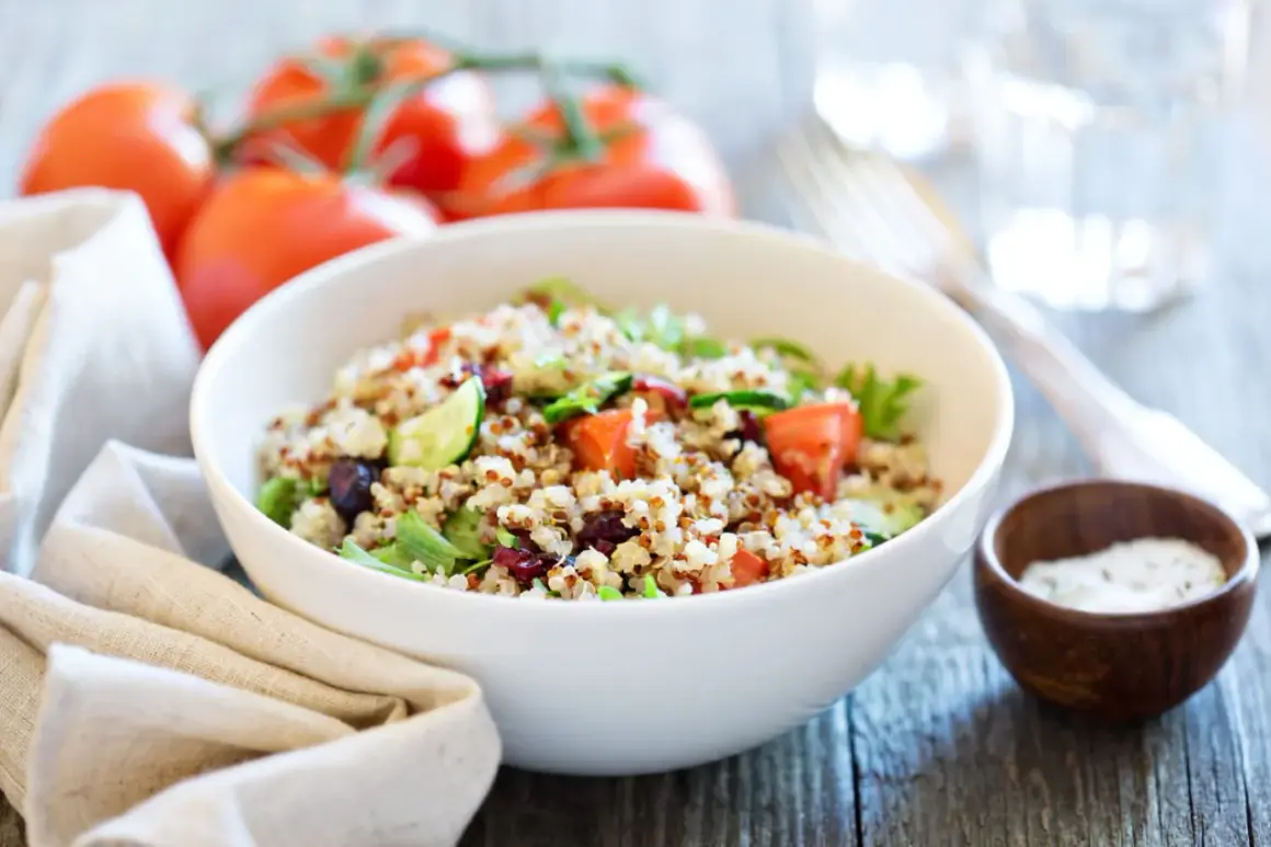 Salade de quinoa colorée avec tomates, concombre et canneberges dans un bol blanc.